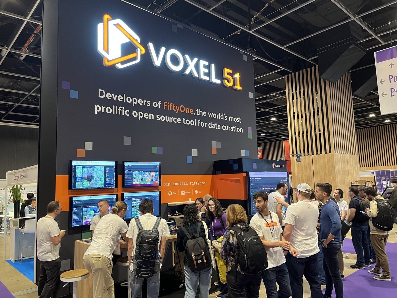 Voxel51 conference booth with a crowd of developers at the demo screens