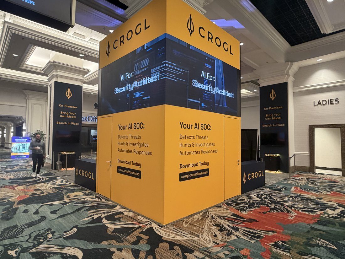 Crogl tower booth wrapped in trident orange with a wraparound video screen and Your AI SOC messaging