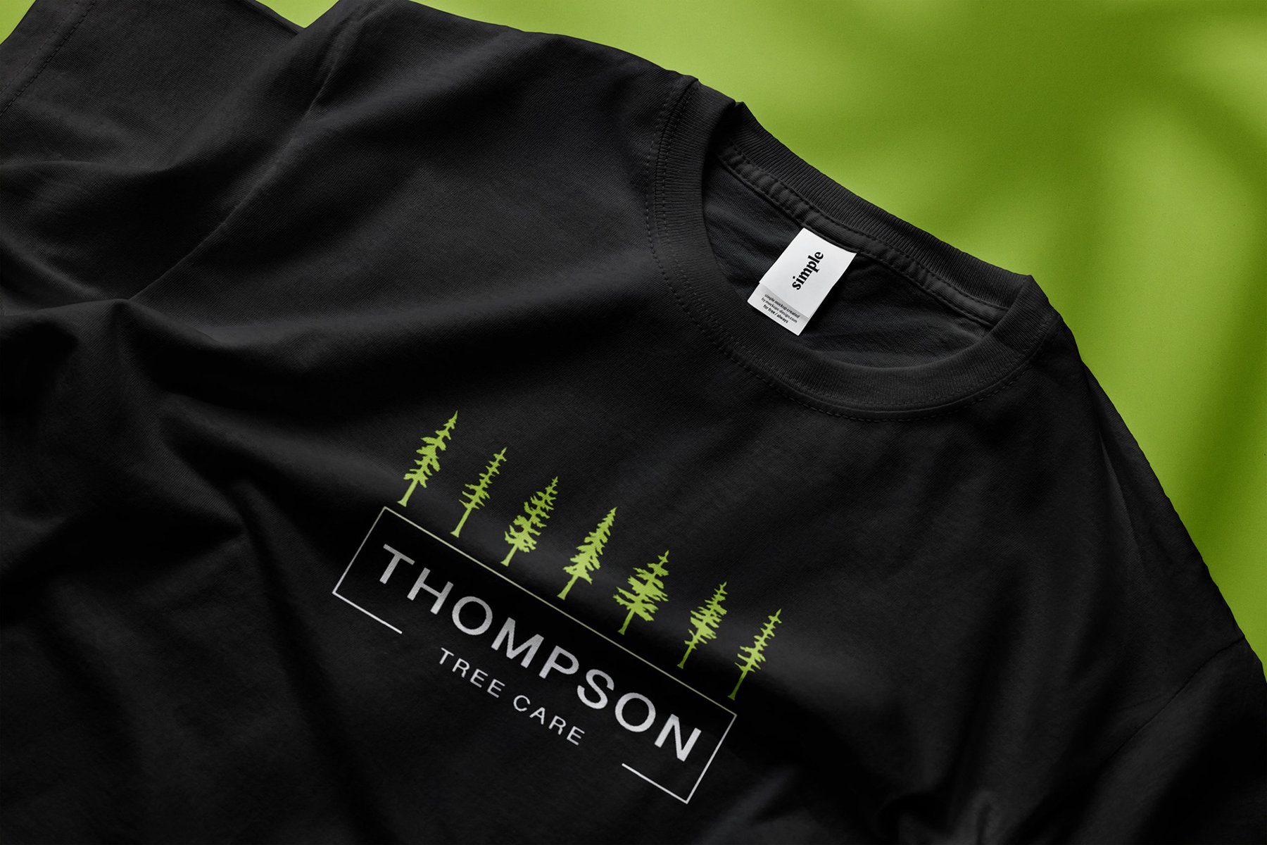 Black Thompson Tree Care t-shirt with the pine tree logo on a green background